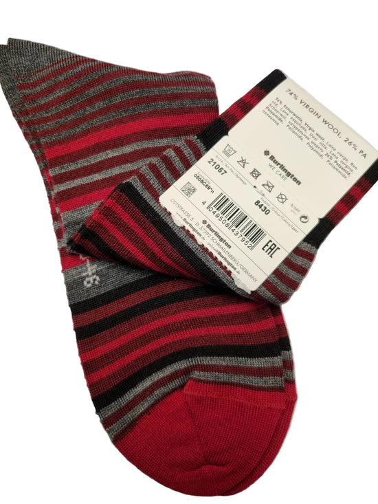 A pair of striped wool socks with red, black, and gray horizontal bands, featuring a solid red toe and heel. A white paper tag with product details is attached to one sock, and the socks are laid flat on a white background.