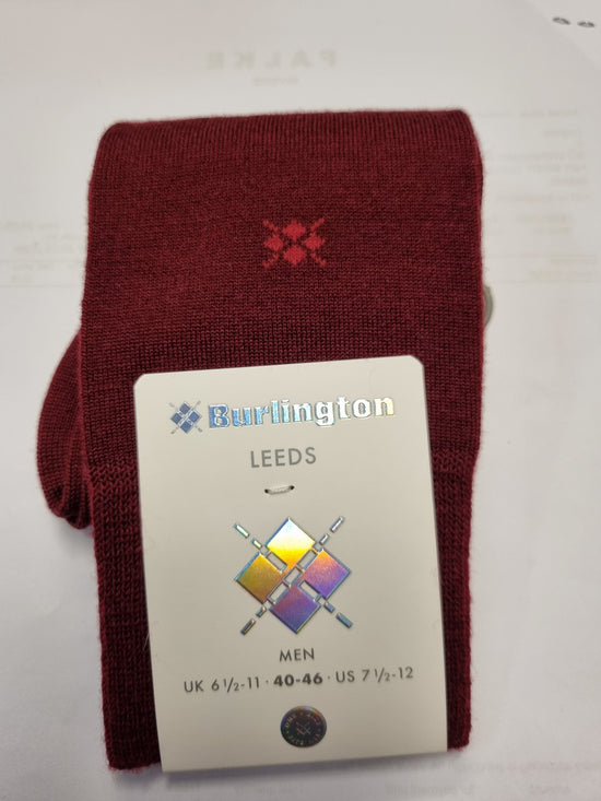 A folded pair of burgundy knit socks with a small red embroidered logo, attached to a white paper tag that reads 'Burlington LEEDS MEN'.